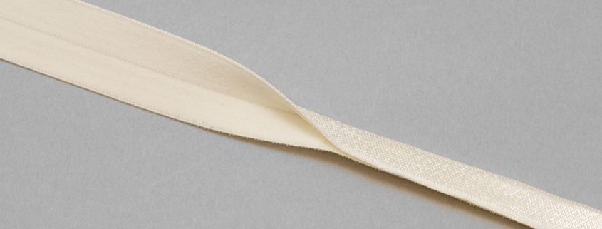 https://www.braandcorsetsupplies.com/wp-content/uploads/2016/06/reversible-fold-over-elastic-binding-EF-5-ivory-or-Pantone-11-0507-winter-white-from-Bra-Makers-Supply-shiny-fold-shown-845x321.jpg